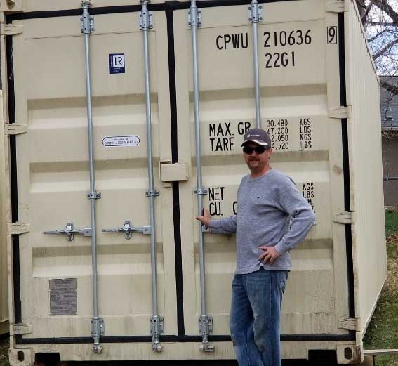 Shane standing beside the doors of a reclaimed shipping container.