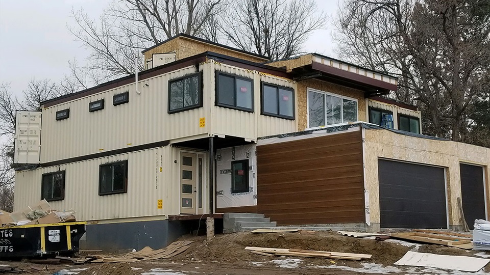 A multi-story shipping-container home during exterior construction.
