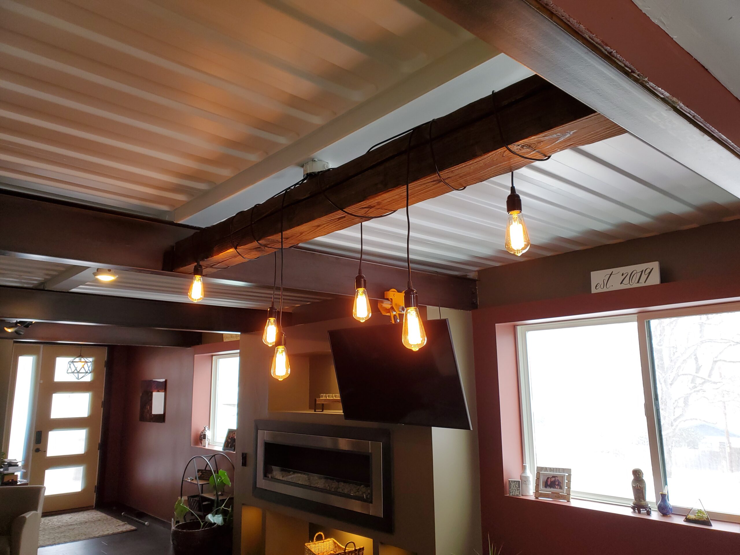 A finished living area with exposed steel beams and pendant lights.