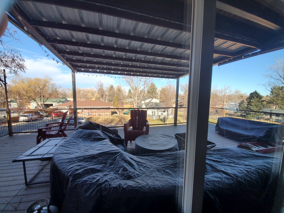 A covered outdoor living space built beneath a steel roof.