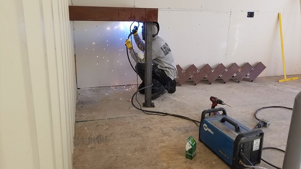 A welder working inside an unfinished shipping container.